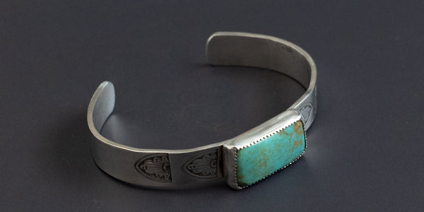 Side view of a Rectangle campitos turquoise stone set in a thick gauge sterling silver cuff, hand stamped and handmade