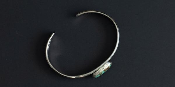 Side view of a green kingman turquoise stone set in serrated bezel and a sterling silver pattern wire. handmade sterling silver cuff