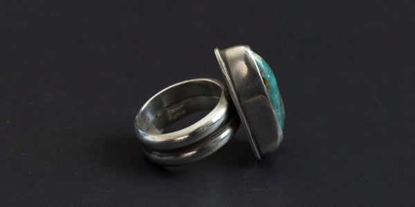 side view of a Silver ring with turquoise stone on a black background