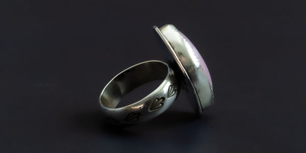 side view of a handmade sterling silver ring with a natural shaped, pink, kunzite stone set in a serrated bezel and a hand-stamped ring shank
