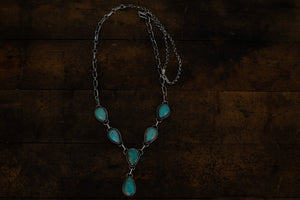 six turquoise stones set into a lariat style necklace of sterling silver