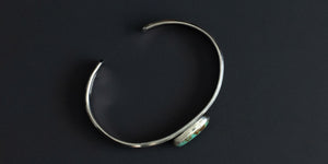 Side view of a green kingman turquoise stone set in serrated bezel and a sterling silver pattern wire. handmade sterling silver cuff