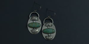 Kingman turquoise oval stones set horizontally in handmade sterling silver earrings with hand stamped fan details above and below the stone
