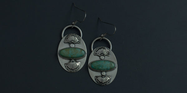 Kingman turquoise oval stones set horizontally in handmade sterling silver earrings with hand stamped fan details above and below the stone