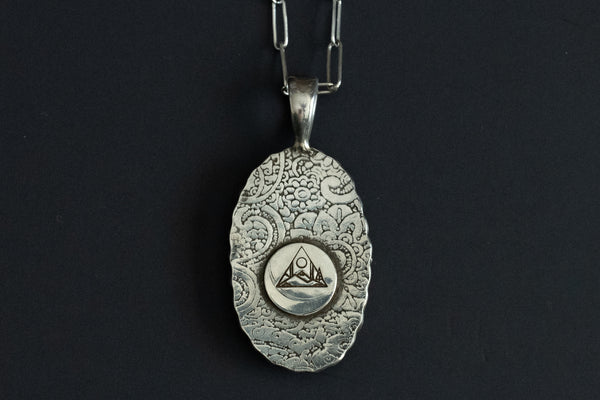 Back view of a sterling silver pendant showing a paisley design stamped into the silver