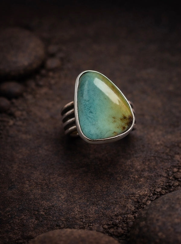 Blackjack turquoise stone set in .925 sterling silver setting with a plain bezel and a wide, pattern wire ring band