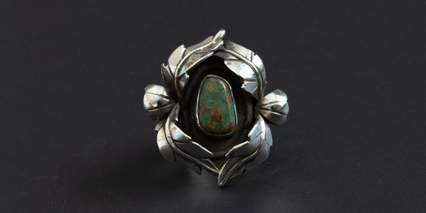 Handmade sterling silver ring with leaf details surrounding a small turquoise stone