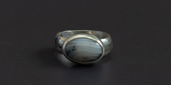 oval moss agate stone set in a handmade sterling silver ring with a plain bezel and hand stamped ring shank