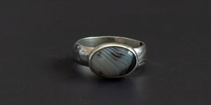 oval moss agate stone set in a handmade sterling silver ring with a plain bezel and hand stamped ring shank